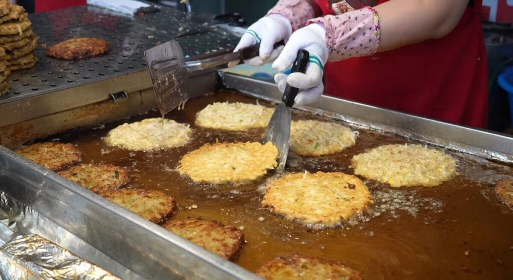 Bindaetteok mung bean pancakes frying at a Gwangjang Market stall
