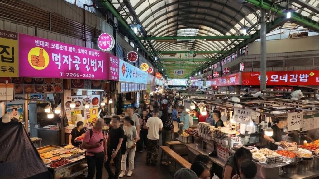 Crowded food alley inside Gwangjang Market with Monyeo Gimbap stall