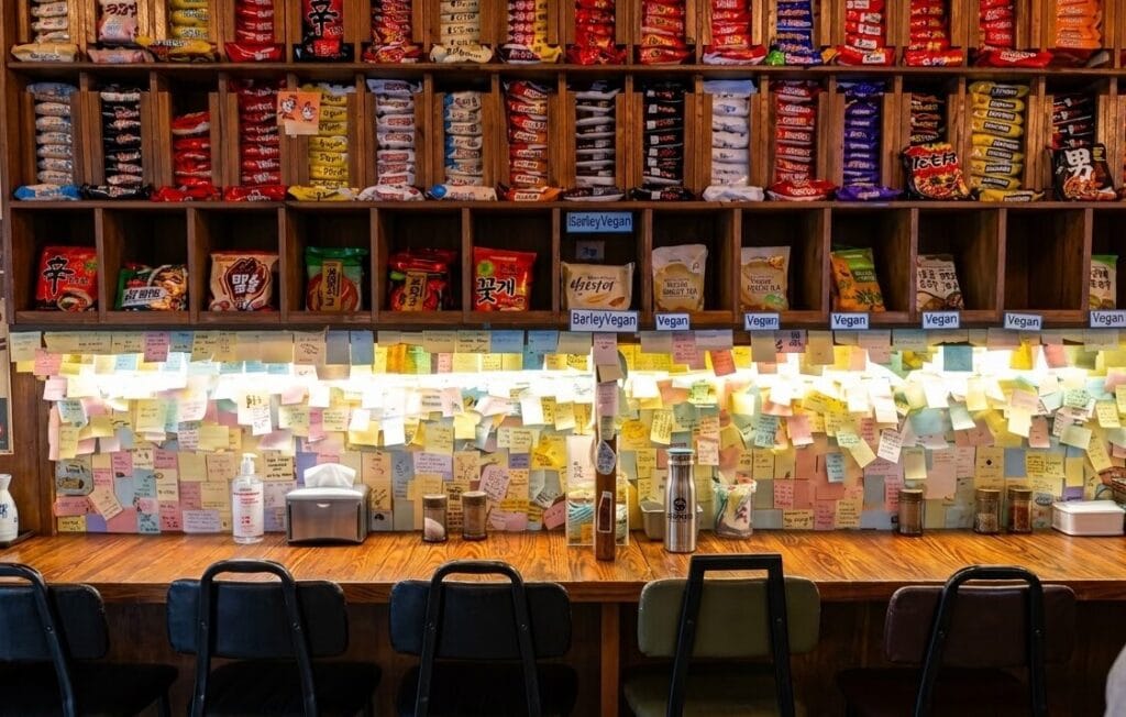 Wall of instant ramen brands and customer sticky notes inside an unmanned ramen shop in Seoul