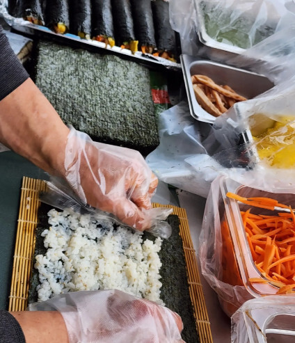 Hands rolling gimbap on a bamboo mat at Eunjune Restaurant