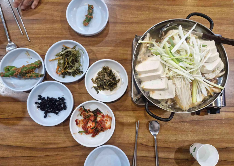 Tofu hot pot with green onions and side dishes at Woorikong Sundubu