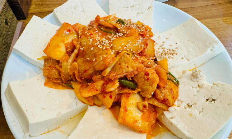 Sliced fresh tofu served with stir-fried pork and kimchi at Woorikong Sundubu